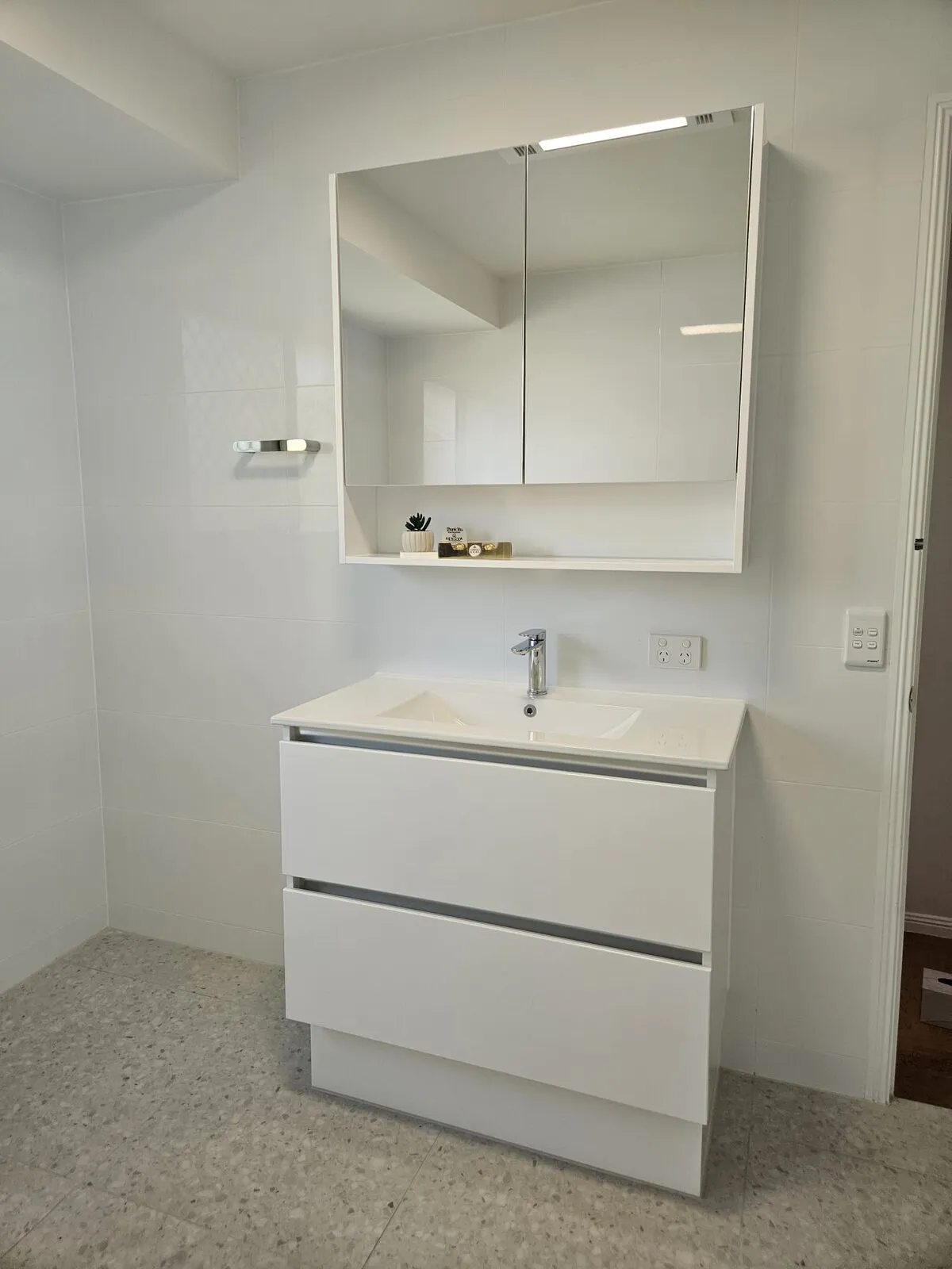 Wall-hung two-drawer bathroom vanity with an integrated basin, below a mirrored shaver cabinet